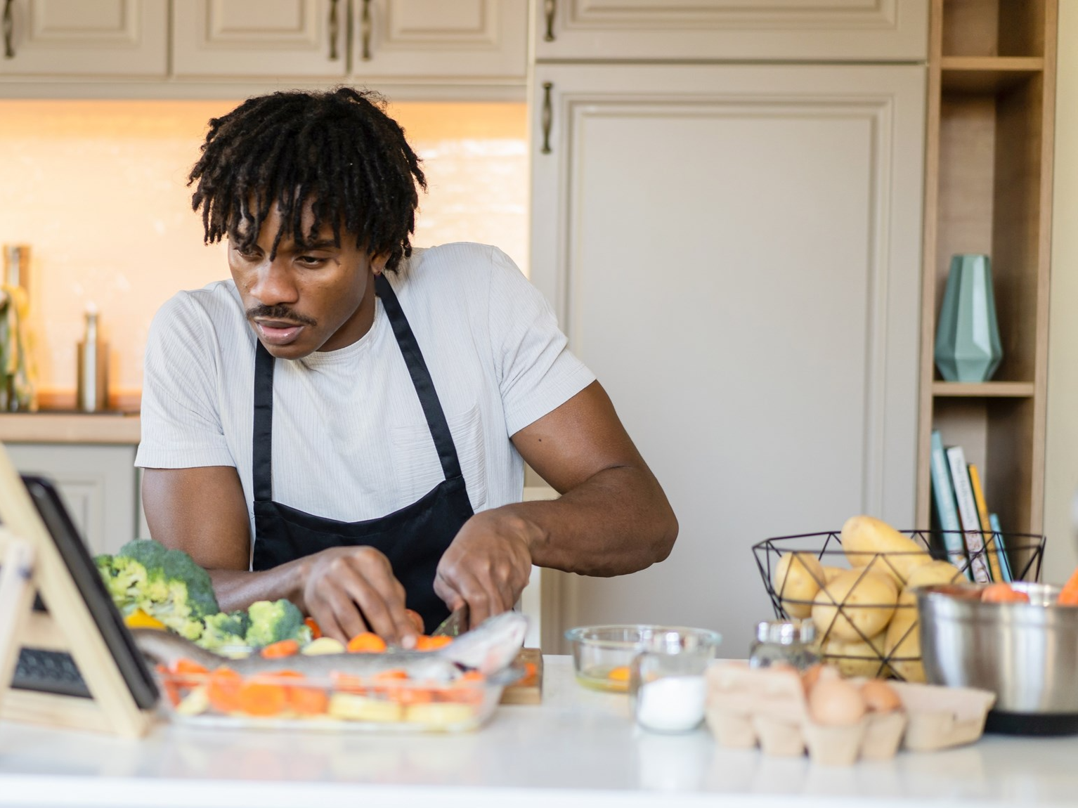 A man chopping vegetables on a cutting board in a kitchen.